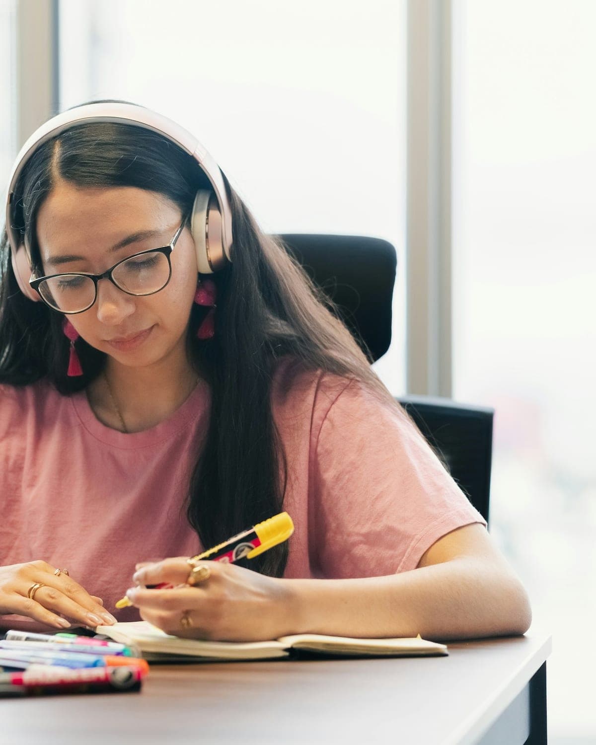 A student wearing headphones writing notes in a notebook